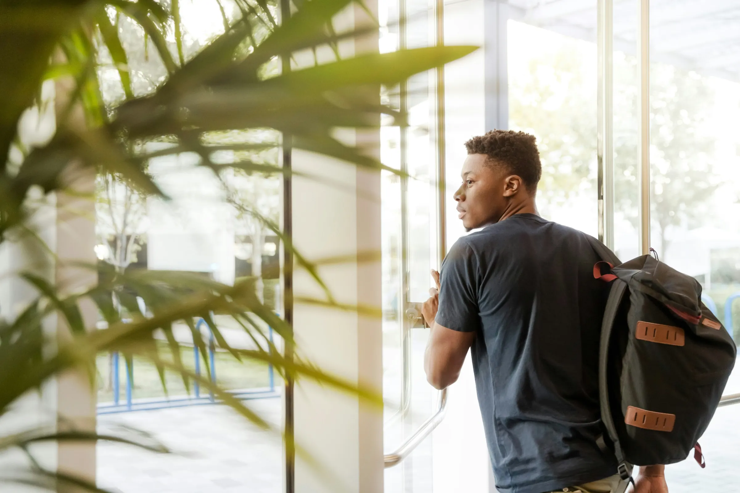 A student with a backpack walking through a bright building